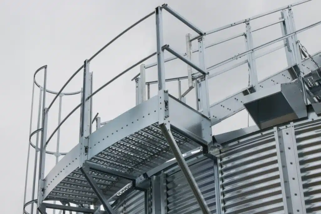 Plataforma metálica galvanizada con barandilla de seguridad, escalera de jaula y rejilla tramex en instalación industrial