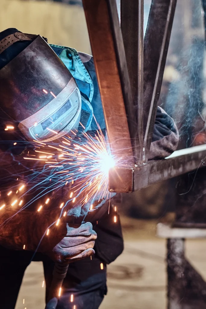 Soldador homologado ejecutando soldadura MIG/MAG en reparación de unión estructural de viga metálica